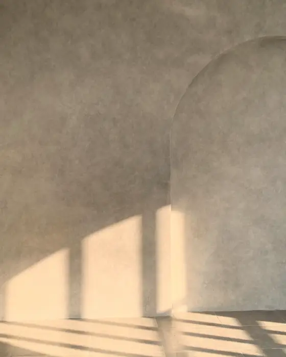 Weiches Nordlicht auf einer verputzten Wand, darüber der Schatten eines Fensterrahmens.